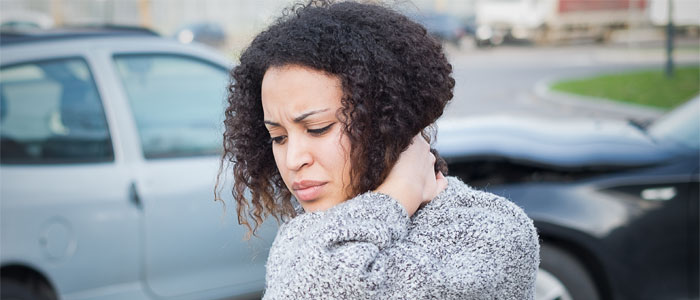 Woman with whiplash holding neck after car accident