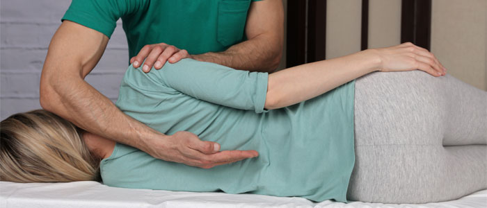 chiropractor checking female patient's spine alignment